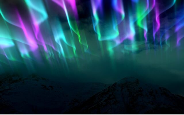 A view of the multiple colors of the Aurora Borealis or Northern Lights over a mountain range.