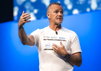 Jeff Clarke, Dell Technologies vice chairman and co-COO, on stage wearing a white t-shirt showing a timeline of Dell's corporate logos, speaks onstage at Day 2 of Dell Technologies World.