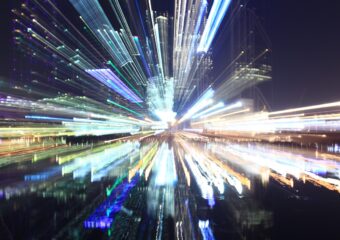 Unfocused image of a city's downtown area at night, with building and city lights radiating outward.