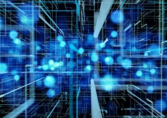 Digitally generated image of rays of light and molecules in high speed motion. They're in shades of blue and teal against a dark background.