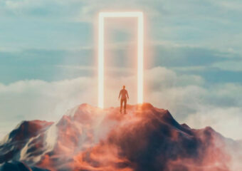 Man facing a portal to a new destination on a mountaintop with cloud layer and blue sky appearing in the background.