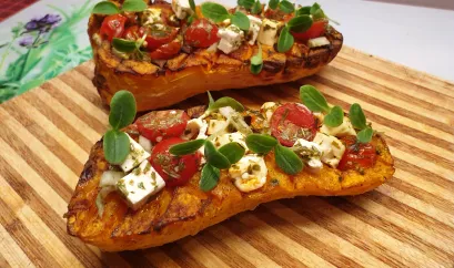 Zwei halbierte Butternut Kürbisse sind mit Feta und Tomaten gefüllt.