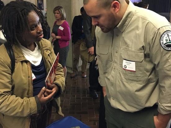 An employee meets with an attendee at a hiring fair