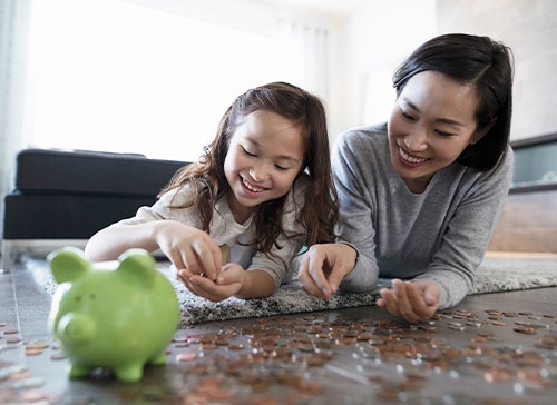 Mother and daughter sorting change for piggy bank