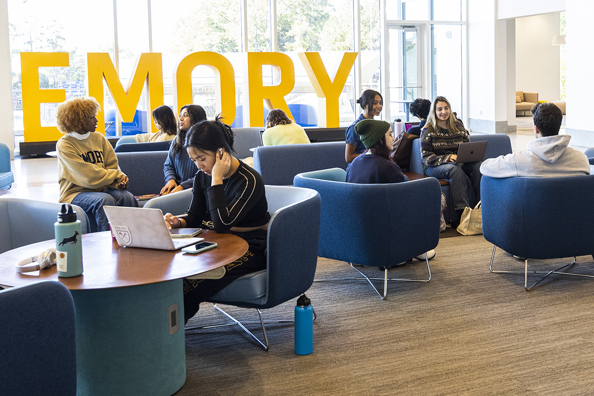 students in the student center by the Emory sign