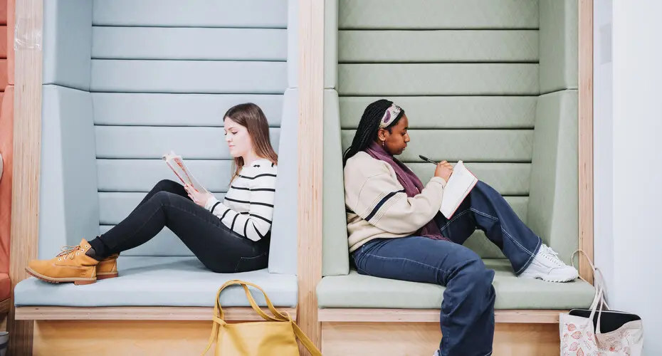 Two students studying back to back in pods on Penryn Campus