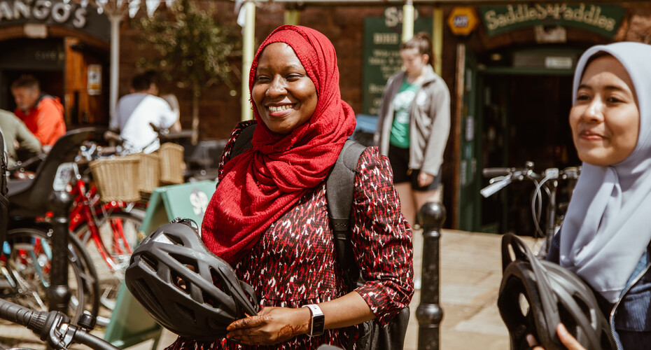 Two students holding cycle helmets, renting bikes at Exeter Quay