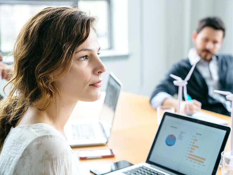 Businesswoman sitting infront of laptop with graphs on screen