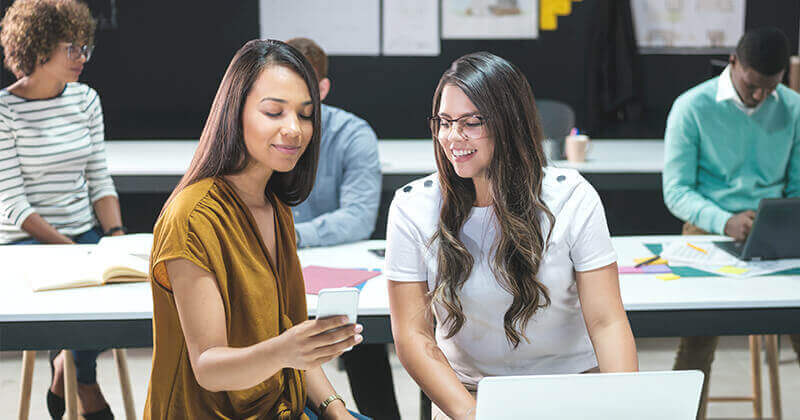 female coworkers looking at smartphone