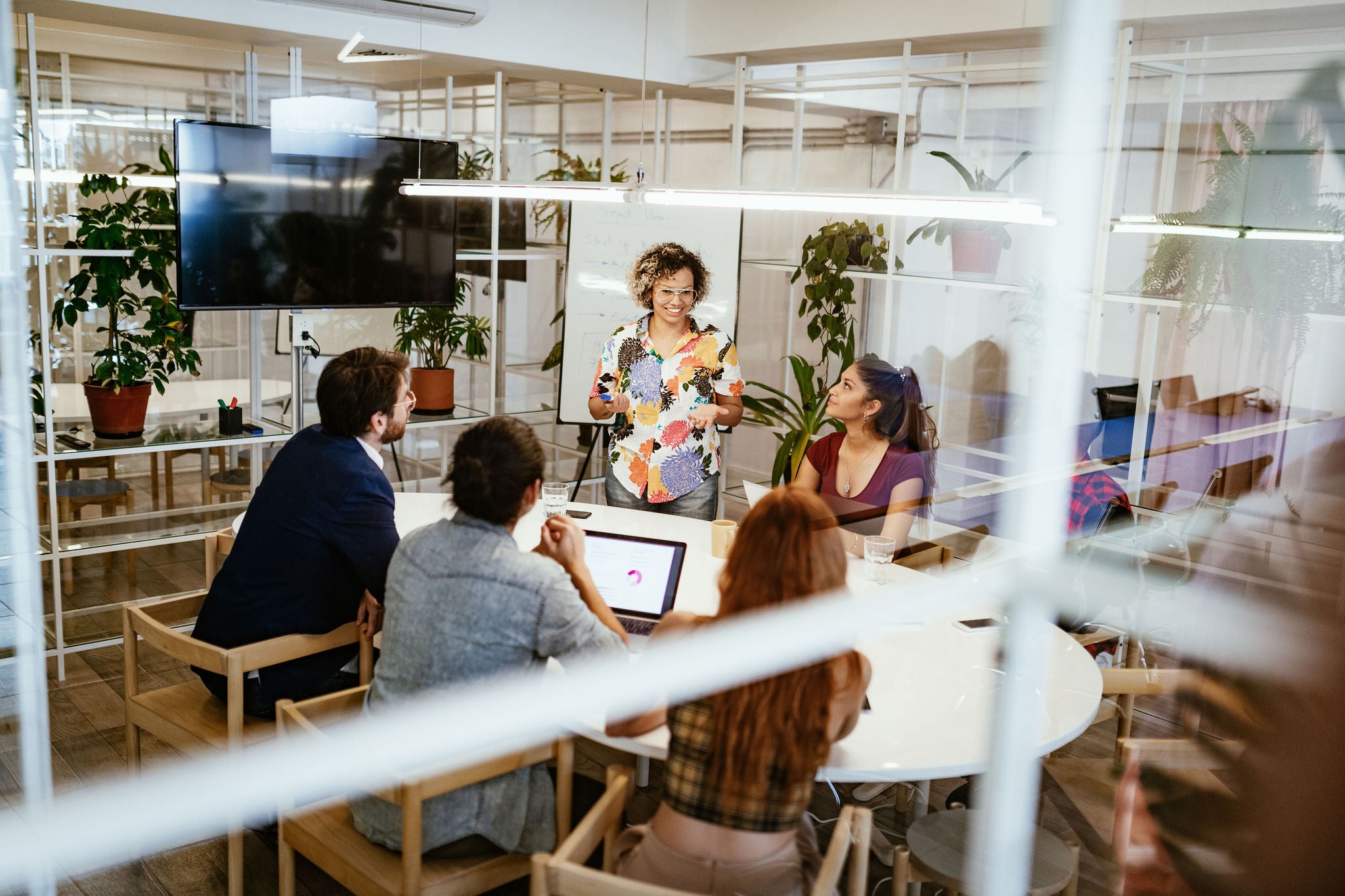 Group of creative entrepreneurs and business people working together in modern eco-friendly office with plants and recycled materials