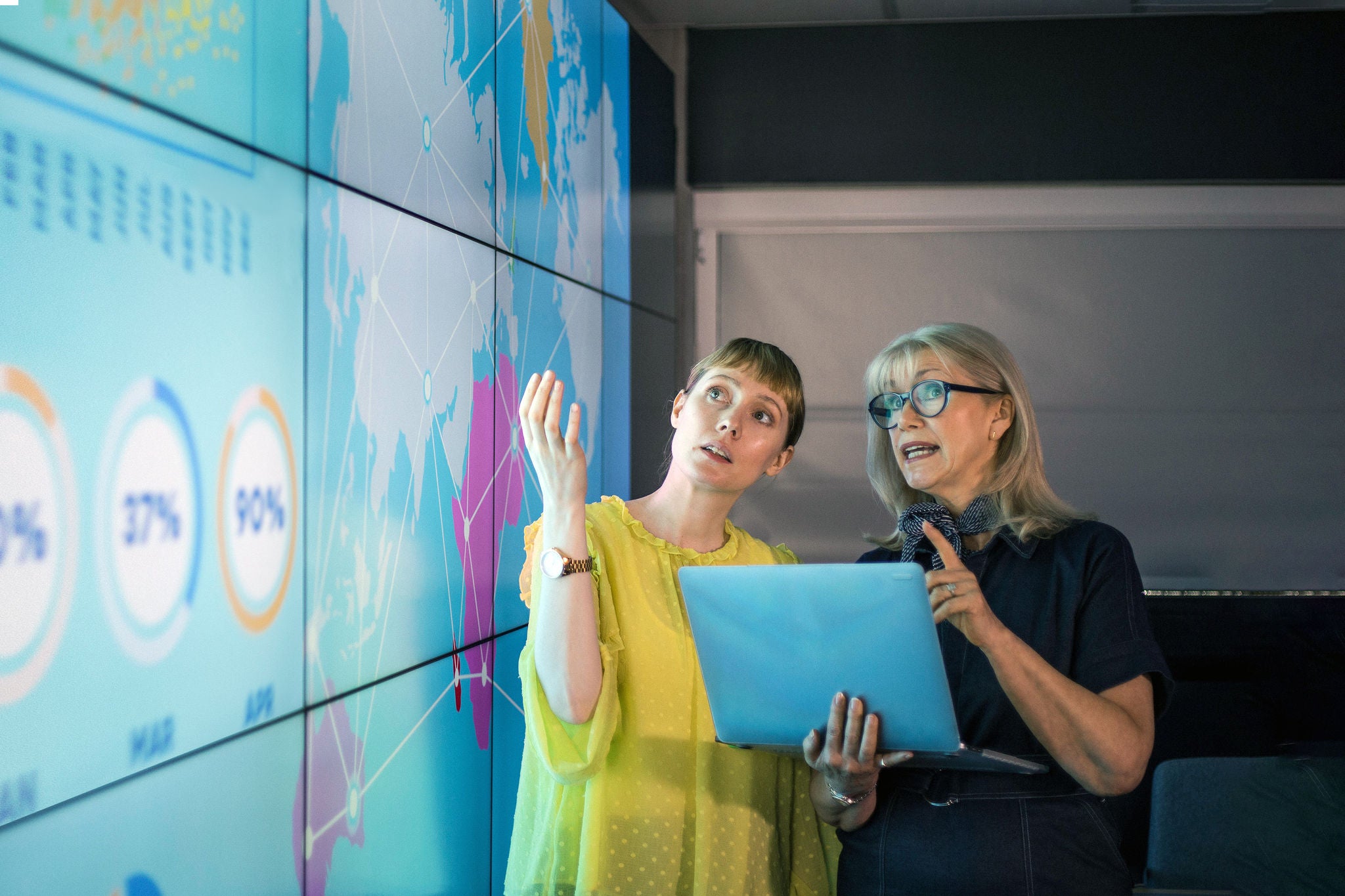 Businesswomen discussing ideas at information wall