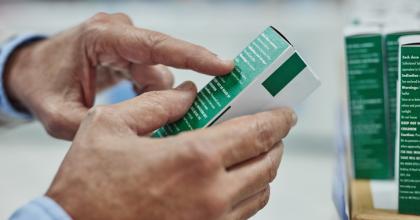 Cropped shot of a man reading the label on a box of medicine in a pharmacy