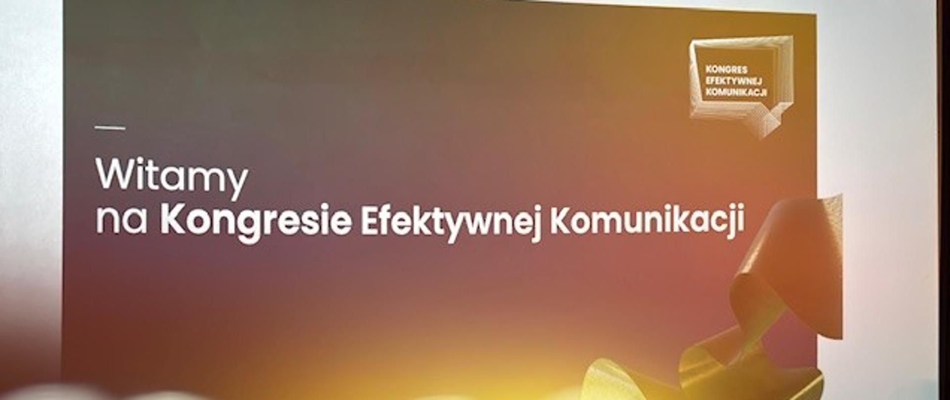 Kongres Efektywnej Komunikacji - przed rozpoczęciem obrad; na wielkim ekranie napis "Witamy na Kongresie Efektywnej Komunikacji", poniżej pięć pustych krzeseł dla panelistów