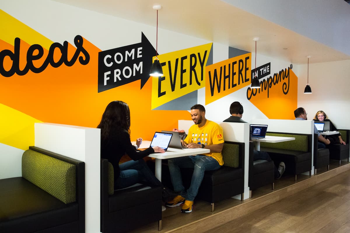  Picture of young workers in booths with a sign in the background that says 