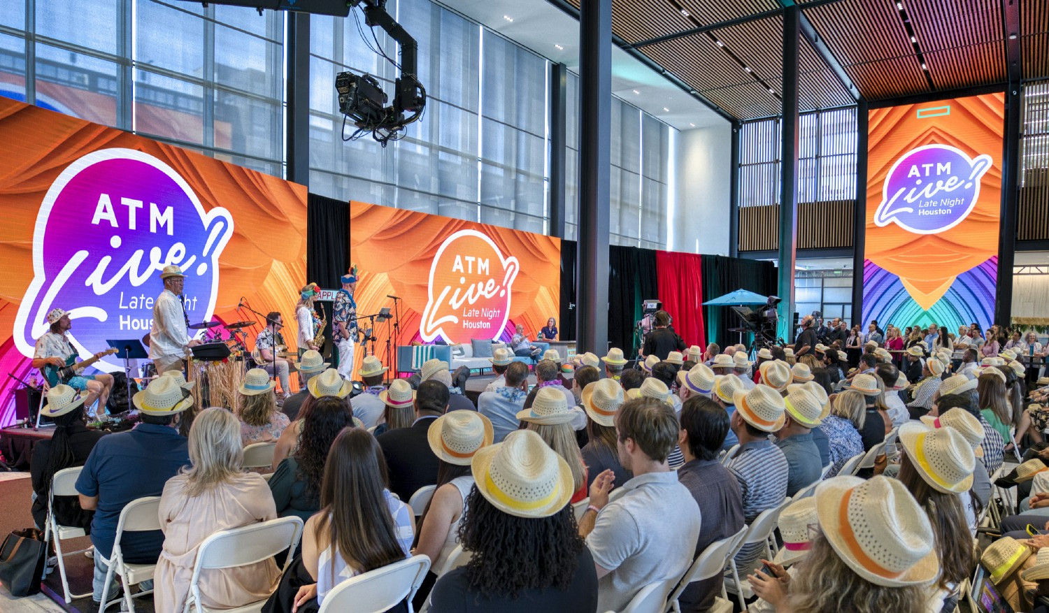 All Team Meeting taking place in HPE's Houston headquarters lobby featuring a live band, host, and fun theme.