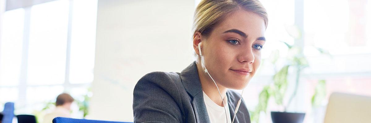 girl with headphones looking at computer