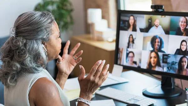 A woman speaks to colleagues on a video connection.