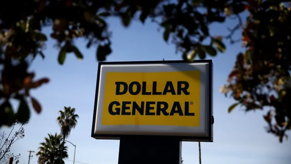 A yellow and black "Dollar General" sign framed by leaves.