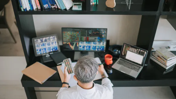 A person sits in front of four screens.