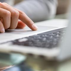 A close up of a woman using the mouse pad on a laptop. Image by LDprod via Shutterstock