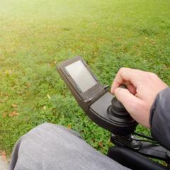 A close-up of the hand of a person driving an electric wheelchair. Image by 24kProduction via Shutterstock