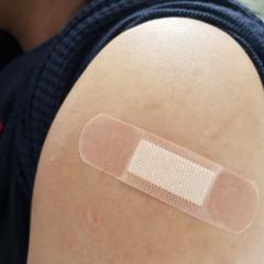 Close-up of a band aid on the upper arm. Image courtesy of Chanita Chokchaikul via Shutterstock