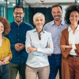 A diverse group of people stand together with their arms crossed