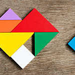 Colorful tangram puzzle in heart shape wait to fulfill on wood background (Concept of happy family, love fulfillment)