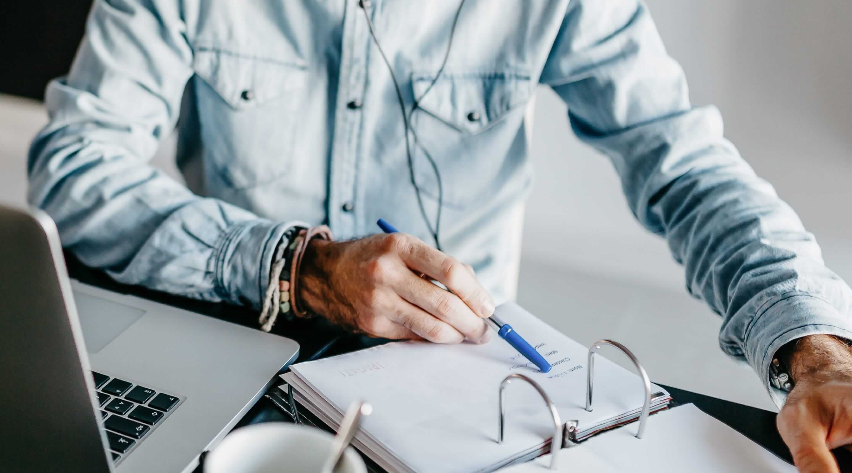 Un homme en chemise prépare les textes juridiques de son site web sur son ordinateur portable.