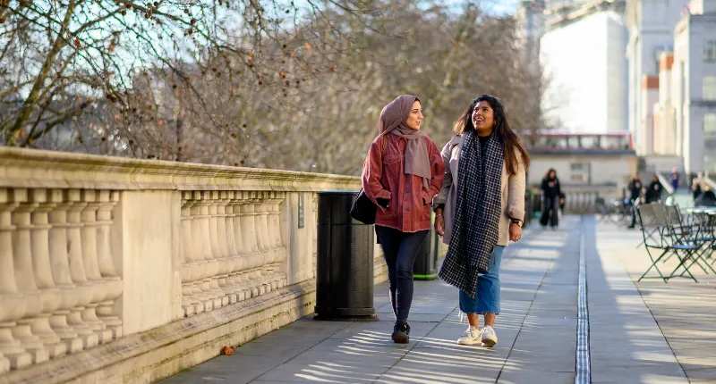 Two female King's students walking and talking.