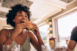 Woman taking a bite out of a sandwich in a restaurant