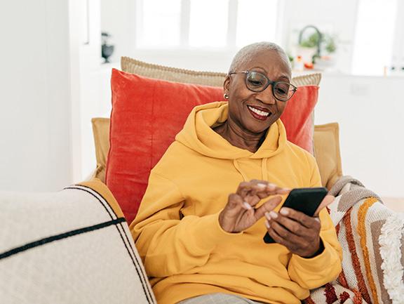 Woman emailing from her phone on her couch