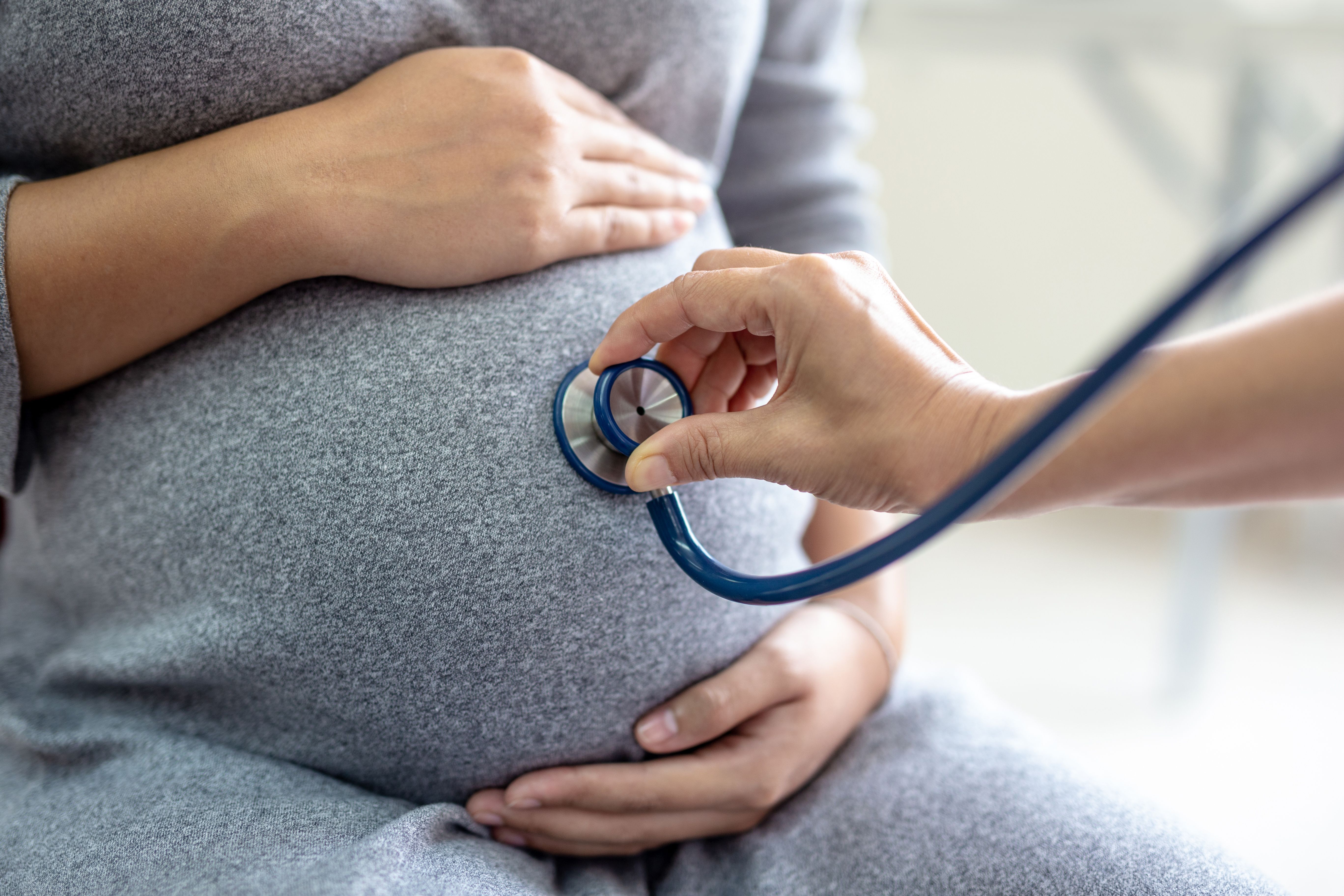 someone holding a stethoscope against a pregnant person's belly | Image credit: ©Pituk stock.adobe.com