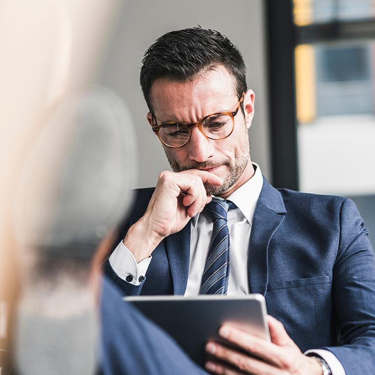 Businessman using digital tablet, sitting in office with feet up