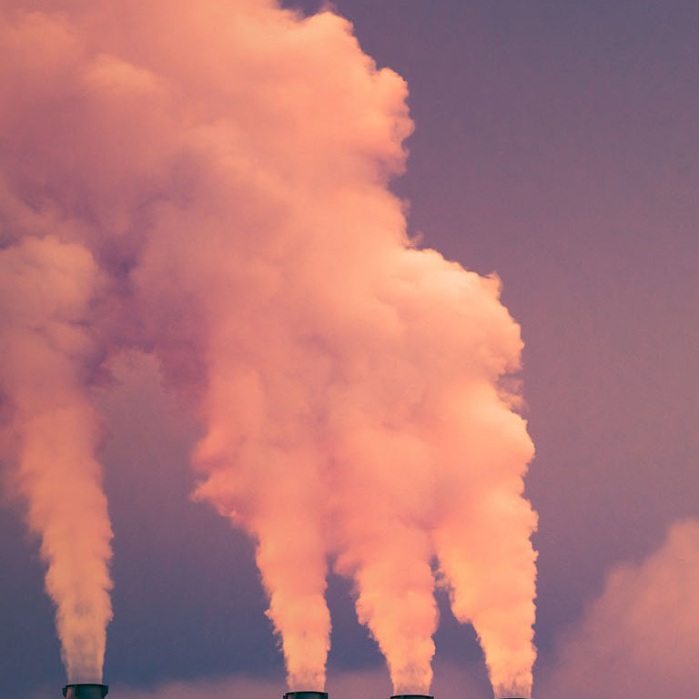 Smoke and steam rising into the air from power plant stacks; dark clouds background; concept for environmental pollution and climate change