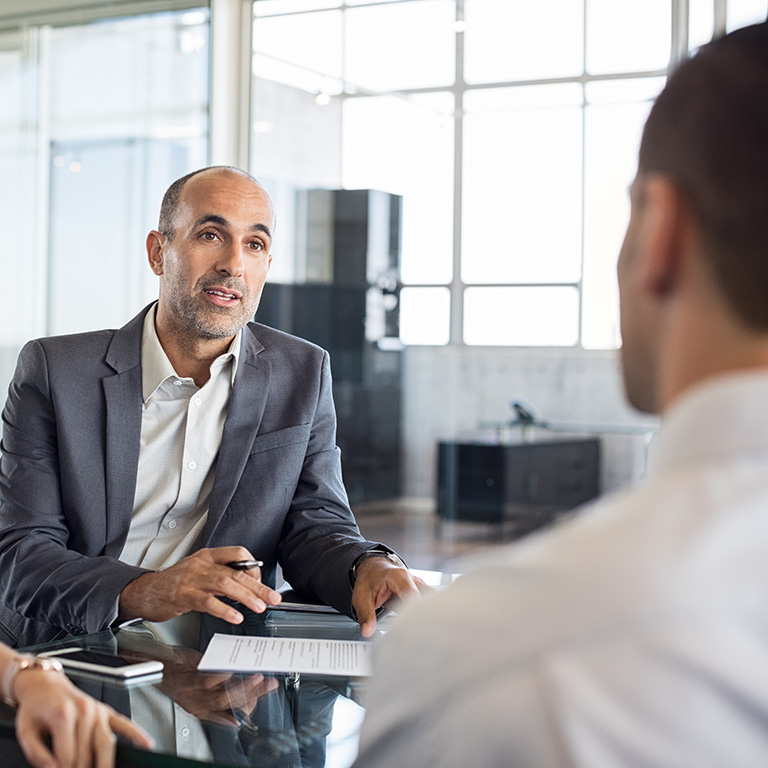 Mature financial agent showing new investment to young couple. Happy financial advisor discussing with a couple their mortgage loan. Happy couple consulting their bank agent about savings plan.