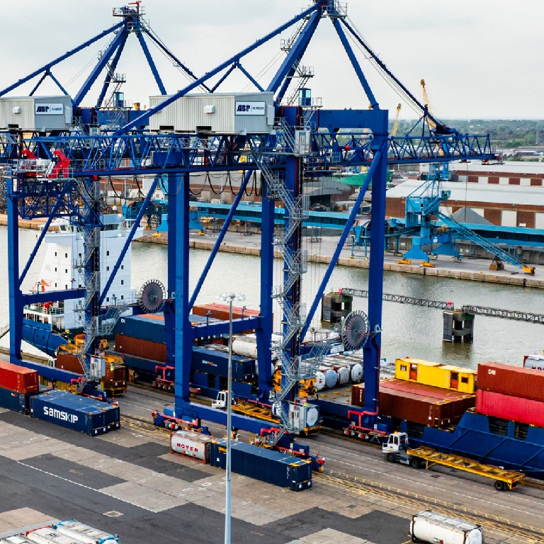 A large port with cranes lifting containers on to a boat