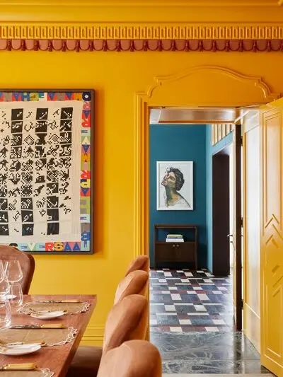 A room with yellow walls and a dining table and chairs