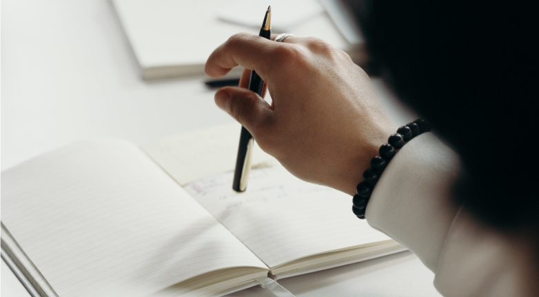 Close up of a woman's hand holding a pen over a notebook