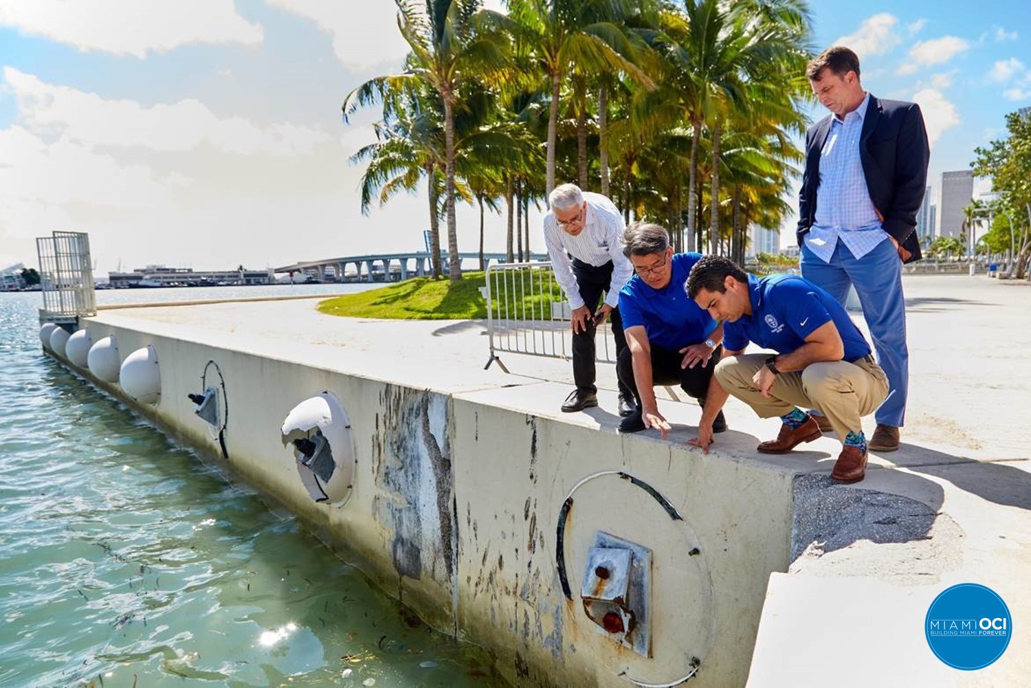 Four men looking over a wall into the water