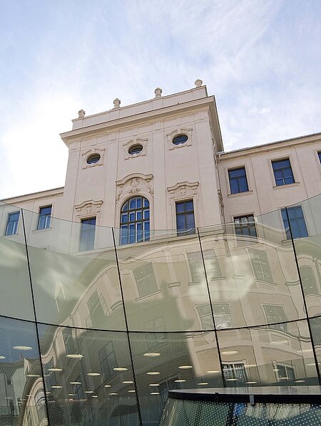 Im Vordergrund ist ein gläserner Trichter des Joanneumsviertels, im Hintergrund die Fassade der Neuen Galerie zu sehen.