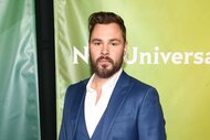 Patrick John Flueger poses in a blue-grey suit.