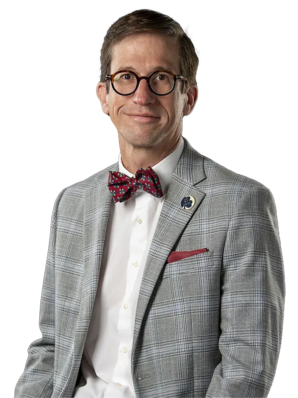 Santiago Schnell looking toward viewer wearing a gray suit with red bowtie.