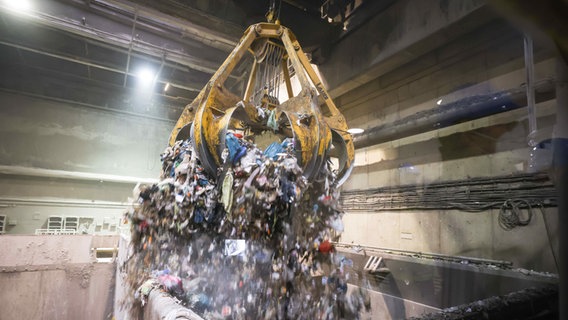 Ein großer Greifer wirft Abfall aus dem Müllbunker in den Verbrennungfsofen in einer Hamburger Müllverwertungsanlage. © pictura alliance / dpa Foto: Christian Charisius