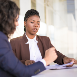 Women in suits look at paperwork at a conference table