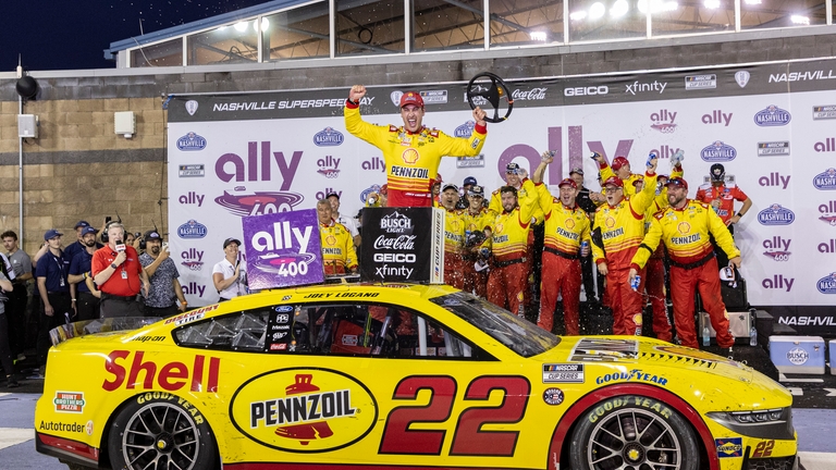 Joey Logano , top,celebrates after winning a NASCAR Cup Series...