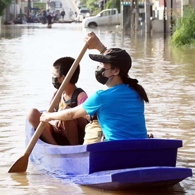 woman and child in a boat on a flooded street