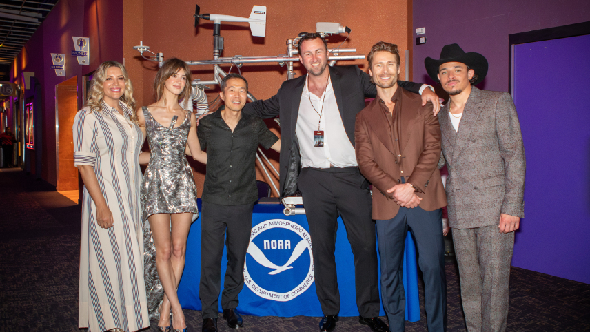 Twisters stars Glen Powell, Daisy Edgar-Jones and Anthony Ramos, along with director Lee Isaac Chung, pose in front of props from Twister during a tour of the National Weather Center and NOAA offices in Norman, Oklahoma in May, 2023.