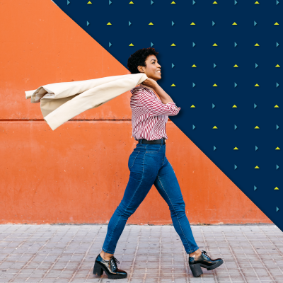 A woman throws her blazer over her shoulder as she walks.