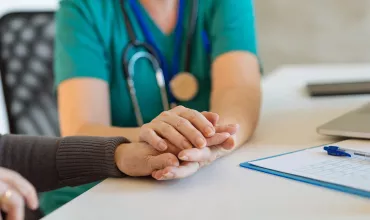 Healthcare professional holding the hands of an elder patient